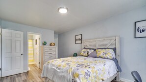 Ein Schlafzimmer mit Bett, Kommode, Stuhl und einer Tür zu einem anderen Raum.