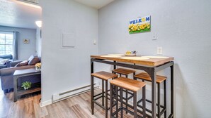 Eine Küche mit einem Holztisch, Barhocker, einem Fenster und einem an der Wand befestigten Schild.