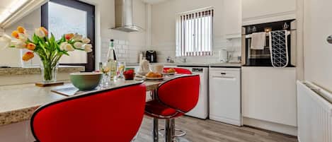 A modern kitchen with white cabinetry, a built-in oven, and a window with blinds.