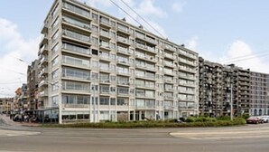A multi-story residential building with balconies, a flat facade, and a clear sky. - Charming Apartment Steps from Blankenberge Beach (Blankenberge)