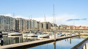 A marina with boats docked, a waterfront promenade, and buildings in the background. - Charming Apartment Steps from Blankenberge Beach (Blankenberge)