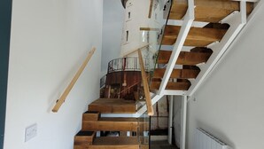 Eine Treppe mit Holzdielen und weißen Geländern, die zu einer Plattform mit Heizkörper führt.