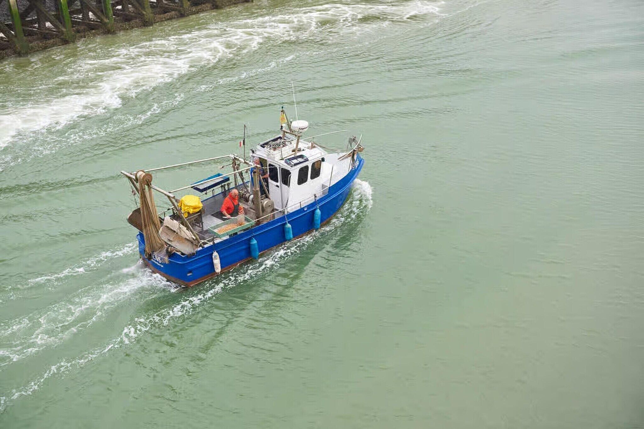 Un bateau doté d’une cabine, d’un pont et laissant une vague derrière lui.