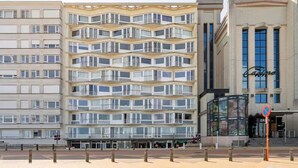 Un hotel de varios pisos con balcones, un letrero de casino y un paseo para peatones.
