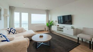Una sala de estar moderna con un sofá, una mesa de centro, un televisor y una planta.