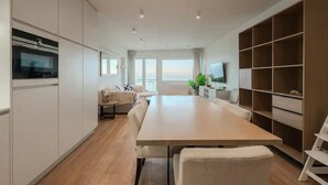 Una cocina moderna con comedor, armarios empotrados, un amplio ventanal con vistas y un televisor.