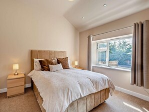 A bedroom with a bed, nightstands, a window with curtains, and a view of trees. - 2 Bed in Blakeney (oc-54765) (Awre)