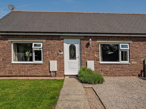 A two-story stone house with a white door, two windows with white frames, and a satellite dish on the roof. - 2 Bed in Blakeney (oc-54765) (Awre)