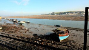 A coastal scene with boats on a muddy shore, a clear sky, and a distant town. - 3 Bed in Bideford (oc-55363) (Appledore)