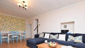A living room with a sofa, a dining table with chairs, and a wooden coffee table with a bowl of fruit. - 3 Bed in Bideford (oc-55363) (Appledore)