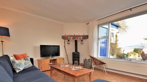 A living room with a sofa, television, table with drinks, and a view of the outdoors. - 3 Bed in Bideford (oc-55363) (Appledore)