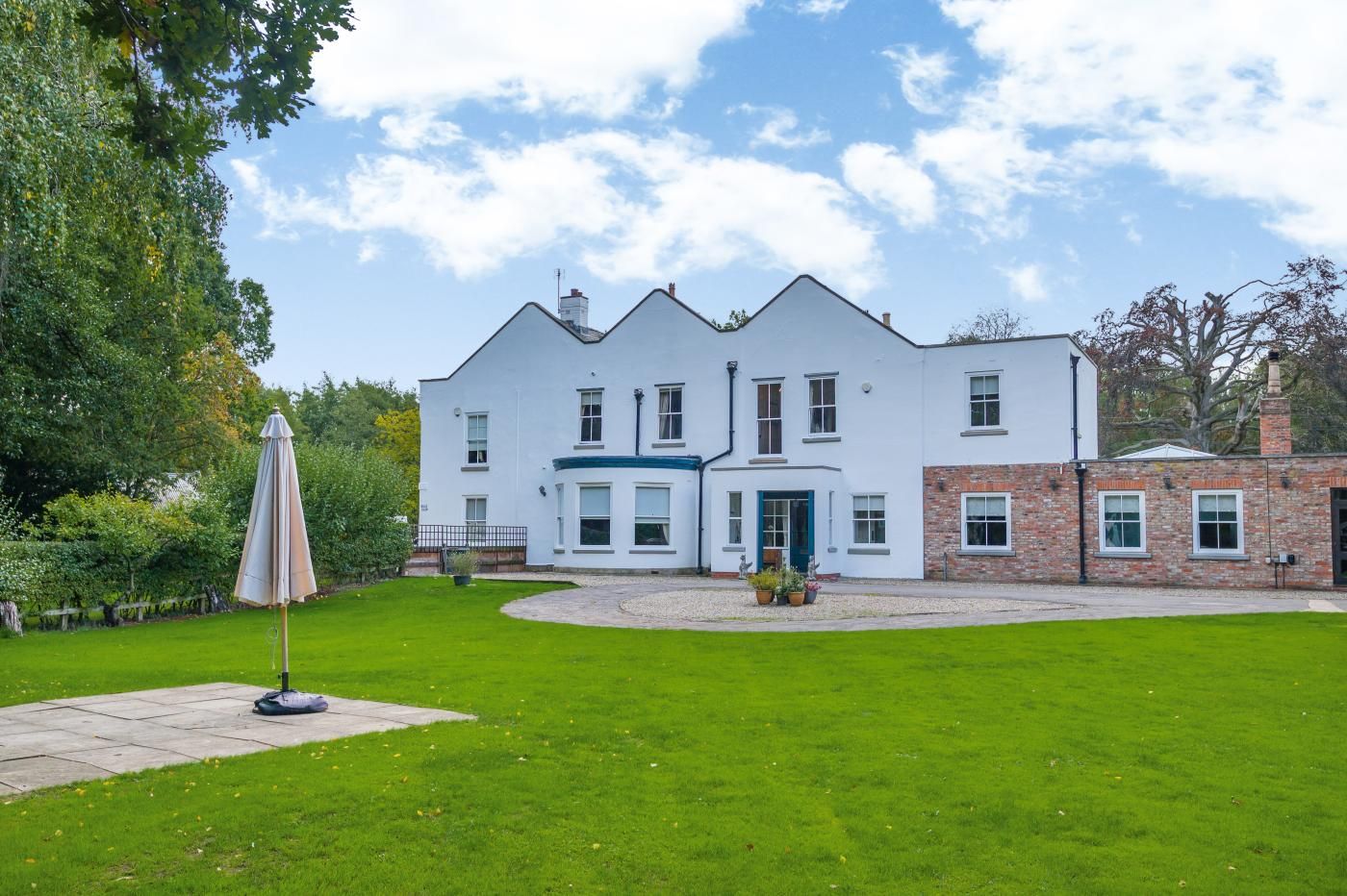 A large, two-story building with a well-maintained lawn and a patio area.
