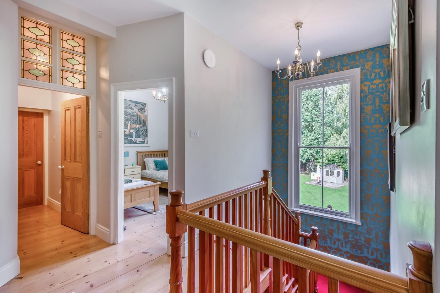 A staircase with wooden railings leading to a bedroom with a bed and a nightstand.