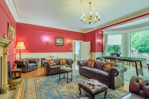 A room with a red wall, a chandelier, a billiards table, and leather sofas. - 4 Bed in York (oc-55738) (Elvington)