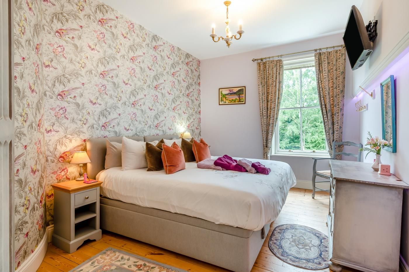 A bedroom with a bed, bedside table, lamp, and a window with curtains.