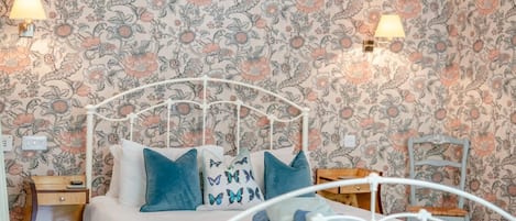 A bed with a white metal frame, blue bedding, and decorative pillows with butterfly patterns.