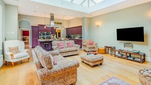 A spacious living room with patterned sofas, a flat-screen TV, and a skylight. - 4 Bed in York (oc-55738) (Elvington)
