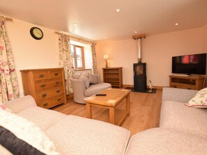 A living room with a sofa, a wooden coffee table, a television, a fireplace, and a clock on the wall. - 2 Bed in Bideford (oc-56720) (Woolfardisworthy)