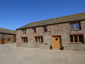 A stone building with a wooden door, windows, and a chimney. - 2 Bed in Bideford (oc-56720) (Woolfardisworthy)