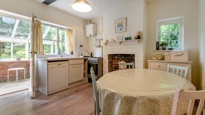 A kitchen with a dining table, a fireplace, and a window. - 4 Bed in Lyndhurst (oc-57407) (Lyndhurst)