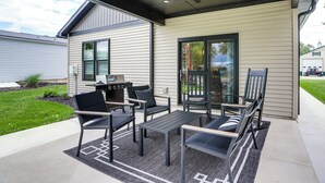 Une terrasse extérieure dotée d’un ventilateur de plafond, d’un barbecue et d’un espace détente avec des chaises et une table.