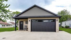 Une maison de plain-pied avec un garage, un porche à l’avant avec une chaise et un petit jardin.