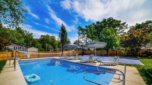 A backyard with a swimming pool, lounge chairs, and a volleyball net. - Stroll to Shore! Michigan City Family Getaway (Michigan City)