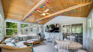 A covered patio with wicker furniture, a ceiling fan, and a TV mounted on the wall. - Stroll to Shore! Michigan City Family Getaway (Michigan City)