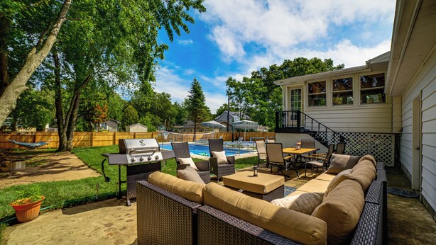 A backyard with a grill, outdoor furniture, a pool, and a house in the background. - Stroll to Shore! Michigan City Family Getaway (Michigan City)