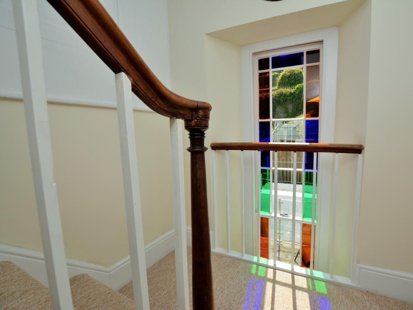 A wooden staircase with a handrail, leading to a room with a window.