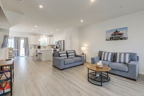 Un salon moderne avec un canapé gris, une table basse et une cuisine en arrière-plan.