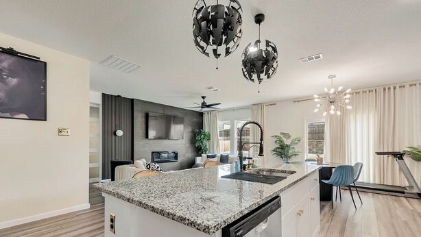 A modern kitchen with a granite countertop, white cabinetry, and a built-in dishwasher. - Great for Families! Glenn Heights Getaway w/ Yard (Glenn Heights)