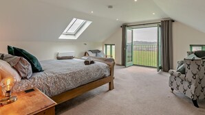 Ein Schlafzimmer mit Oberlicht, einem Bett, einem Sessel und Blick ins Freie.