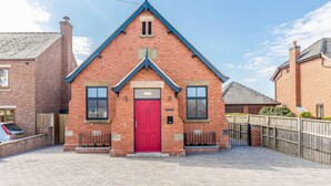 A red brick building with a gabled roof, a red door, and two windows on the ground floor. - 2 Bed in Ellesmere (oc-62544) (Dudleston Heath)