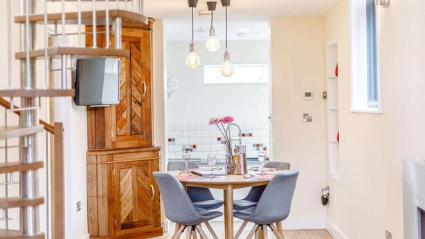 A modern kitchen with a wooden herringbone cabinet, a dining table with chairs, and pendant lighting. - 2 Bed in Ellesmere (oc-62544) (Dudleston Heath)