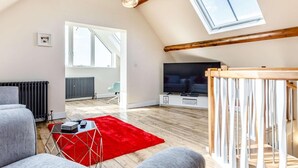A spacious loft with a high ceiling, a television, a red rug, and a staircase. - 2 Bed in Ellesmere (oc-62544) (Dudleston Heath)