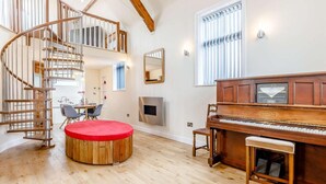 A spacious room with a wooden staircase, a piano, a dining area, and a fireplace. - 2 Bed in Ellesmere (oc-62544) (Dudleston Heath)