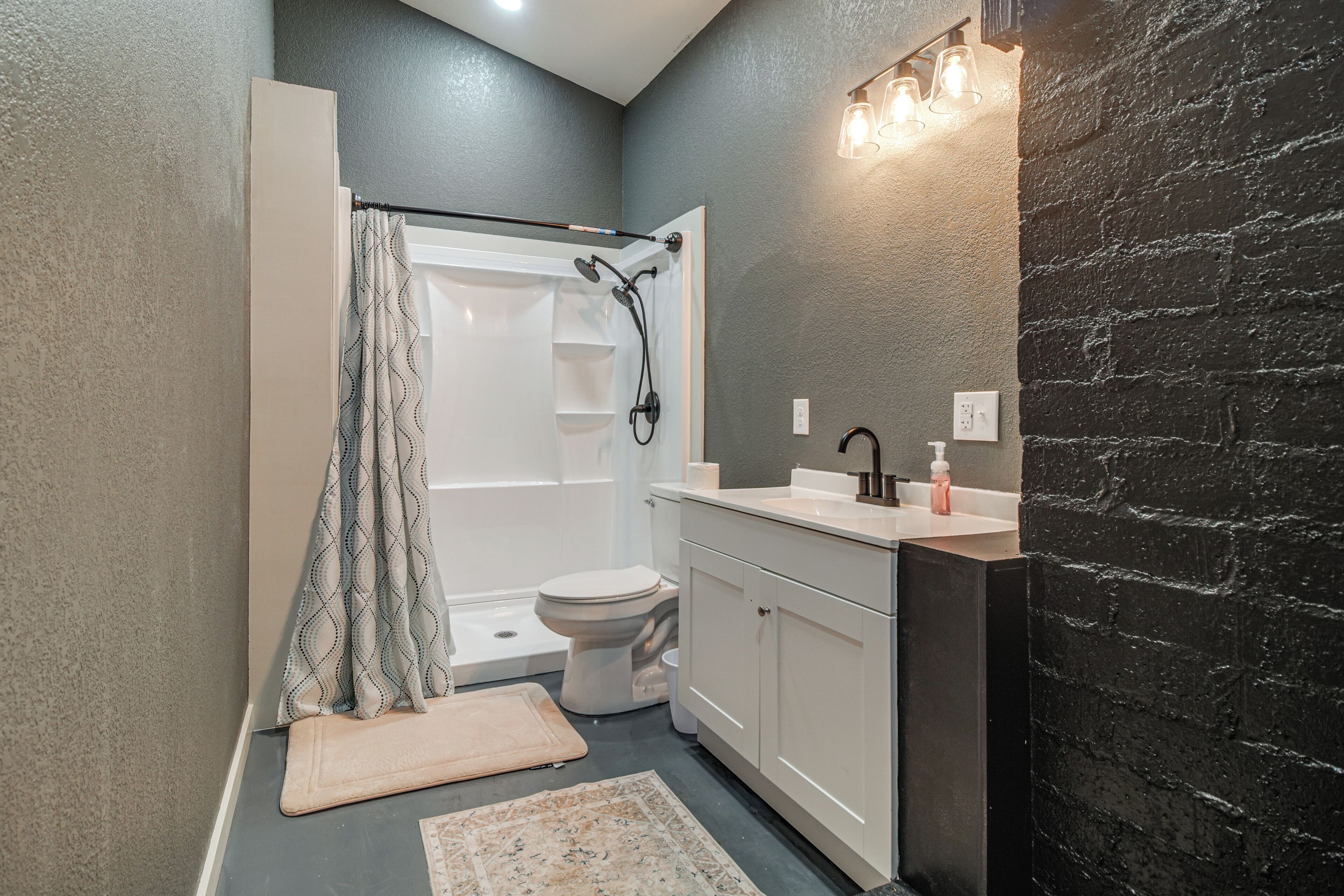 Ein Badezimmer mit Dusche, Toilette, Waschbecken und Teppichboden.