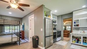 A compact kitchen with a refrigerator, oven, and a dining area with a sofa. - ATV and Boating Base! Home Under 1 Mi to Grand (Disney)