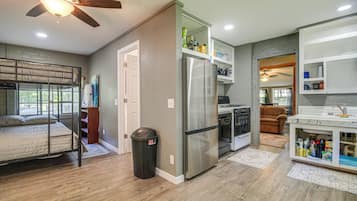 A compact kitchen with a refrigerator, oven, and a dining area with a sofa.