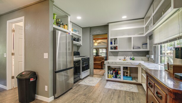 A modern kitchen with stainless steel appliances, wooden flooring, and built-in cabinetry. - ATV and Boating Base! Home Under 1 Mi to Grand (Disney)