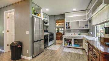 A modern kitchen with stainless steel appliances, wooden flooring, and built-in cabinetry.