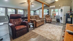 A spacious living room with a brown leather chair, a brown sofa, a wooden coffee table, a patterned rug, and a ceiling fan. - ATV and Boating Base! Home Under 1 Mi to Grand (Disney)