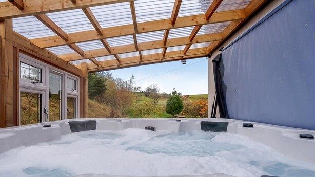 Un jacuzzi con panel de control, vigas de madera y vistas al exterior.