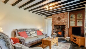 Una sala acogedora con sofá, mesa de centro, chimenea y mueble para la televisión.