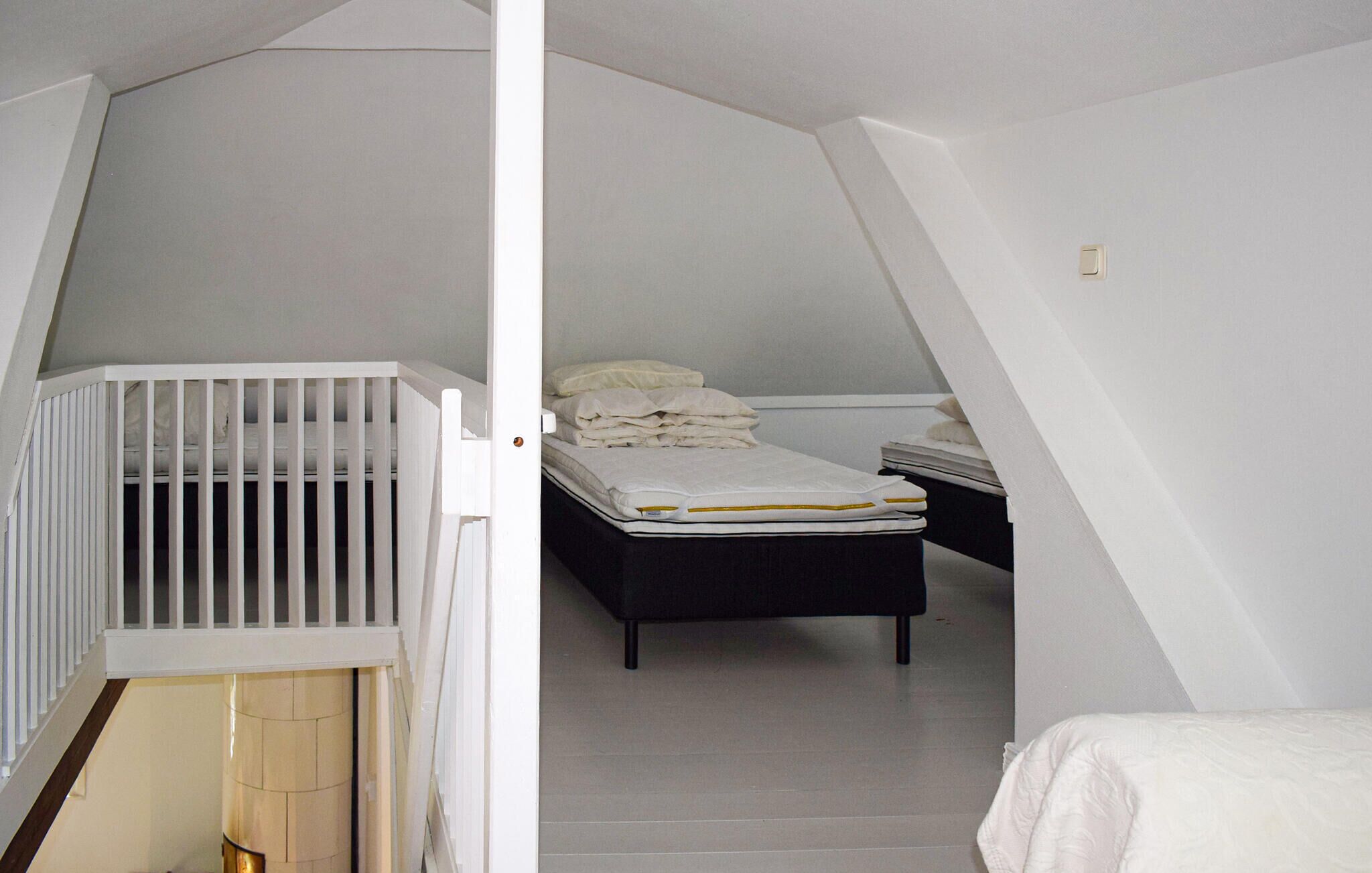 A room with a crib, a bed with pillows, and a small table.