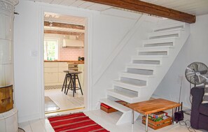 A staircase with white steps leading to an upper floor, a wooden table with boxes underneath, and a fan on the right. - 1 bedroom beautiful home in Tving (Tving)