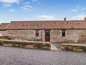 A stone building with a tiled roof, a door, and a small patio area with chairs. - 2 Bed in Bristol (oc-72836) (Chew Magna)