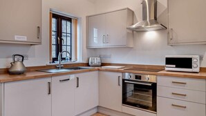 Een moderne keuken met witte kastjes, een roestvrijstalen afzuigkap, een magnetron en een waterkoker.