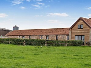 A long, single-story building with a sloped roof, stone walls, and a wooden facade. - 2 Bed in Bristol (oc-72836) (Chew Magna)